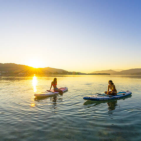 Zwei Damen bei Sonnenuntergang am Woerthersee mit Boot und Paddel